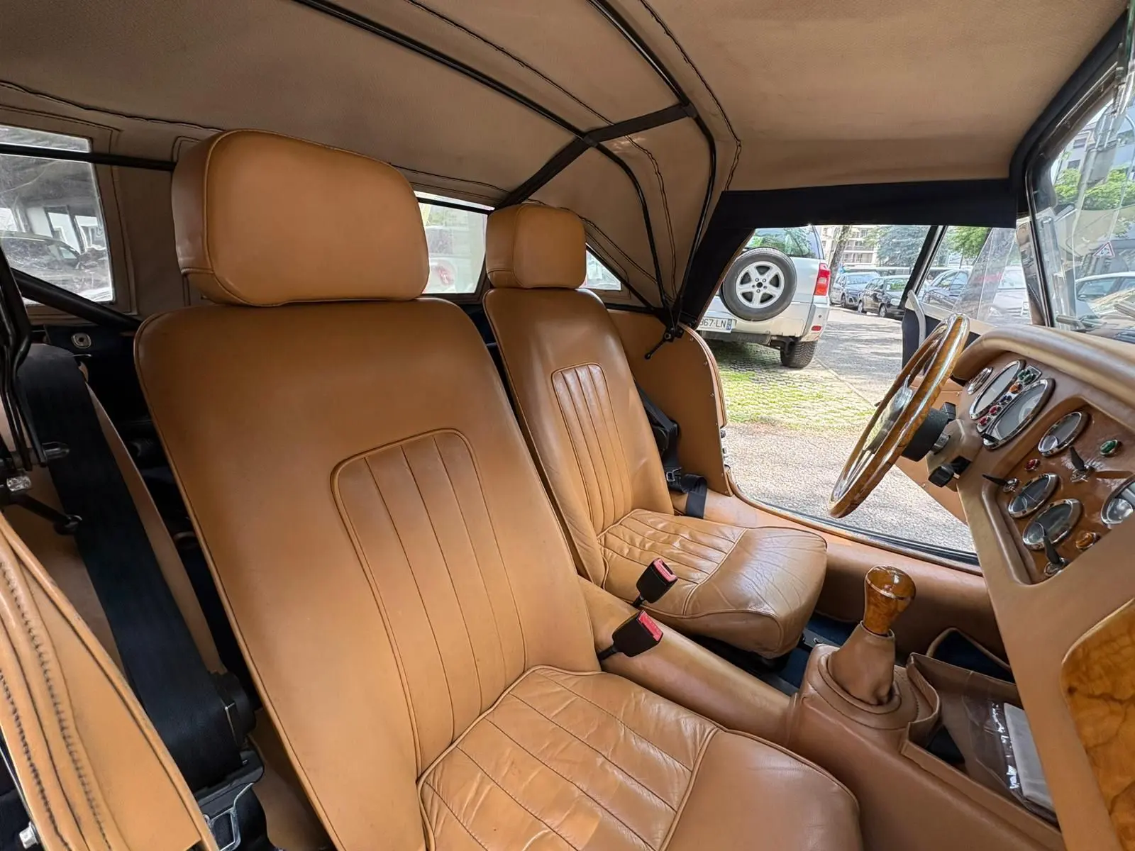 Intérieur de la Morgan Plus 4 1995 vu côté droit, sièges en cuir beige et tableau de bord en bois clair.