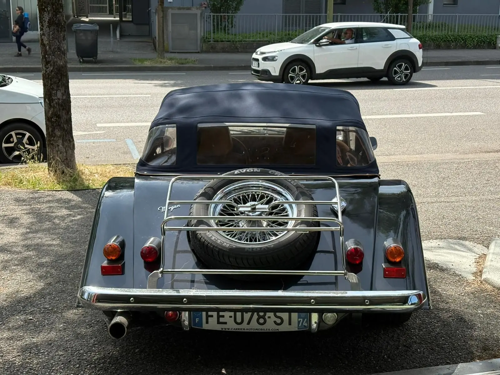 Vue arrière d'une Morgan Plus 4 1995 bleu foncé avec capote noire et roue de secours sur porte-bagages chromé.