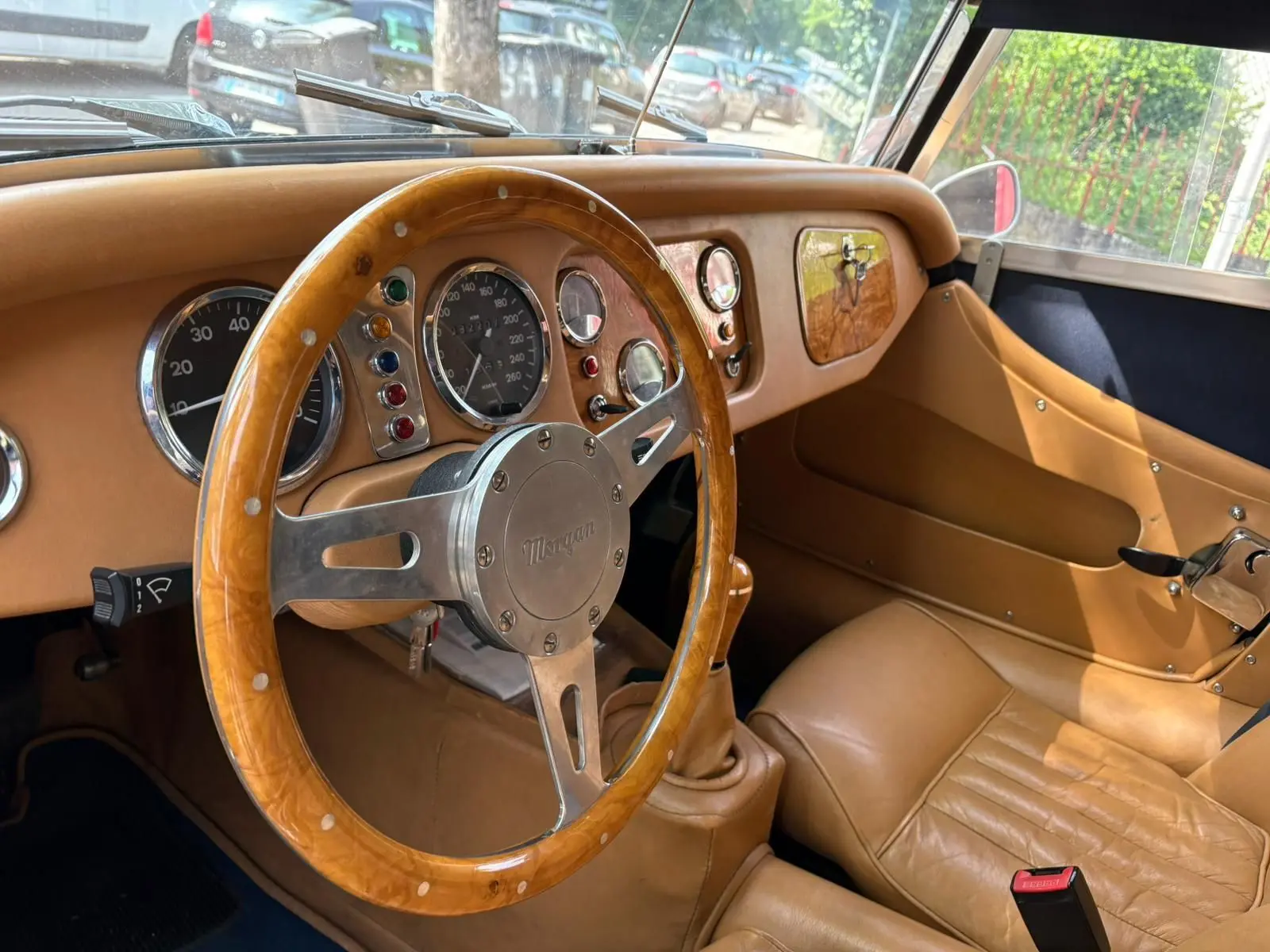 Intérieur beige avec volant en bois et tableau de bord rétro de la Morgan Plus 4 1995, vue côté conducteur.