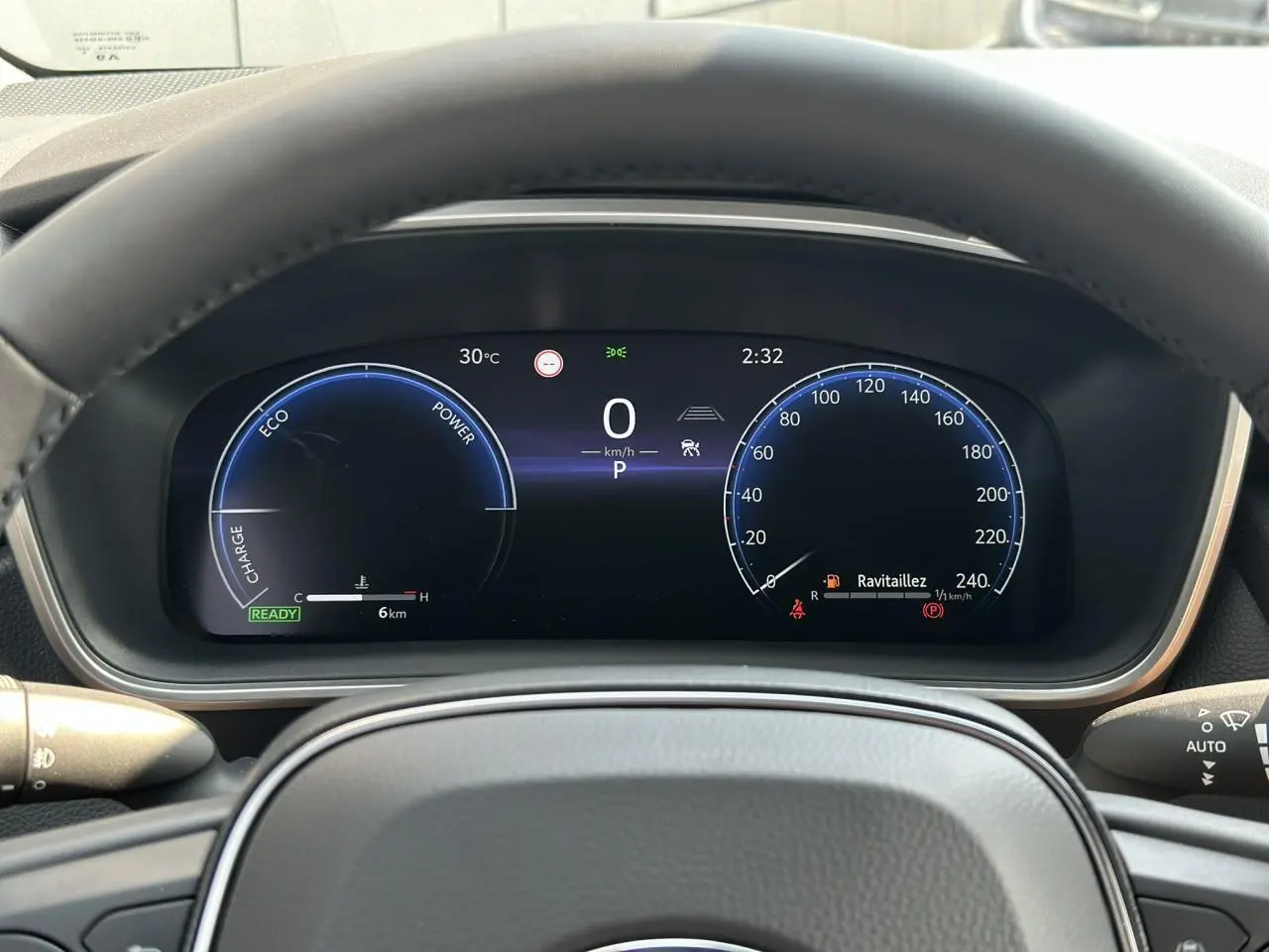 Tableau de bord numérique de la Toyota Corolla Touring Sport 1.8 Hybrid 140 Sport vue depuis le volant, affichage clair et moderne.