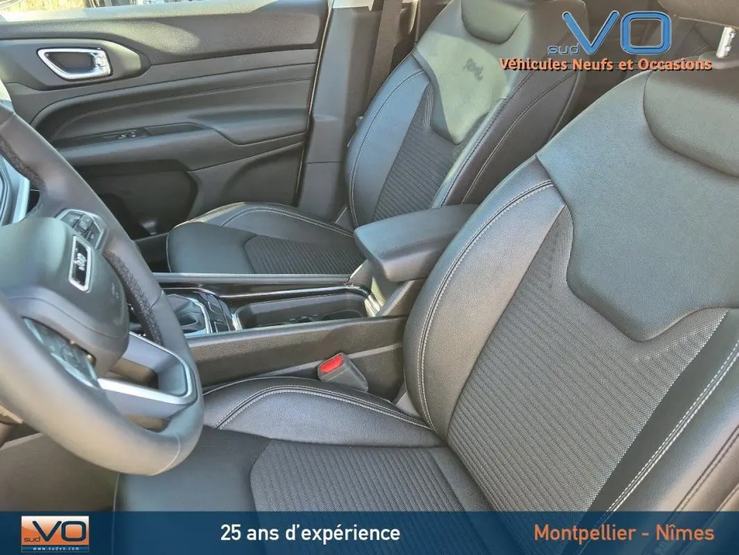 Intérieur du Jeep Compass 2023 montrant les sièges avant en cuir noir et l'accoudoir central entre les deux sièges.