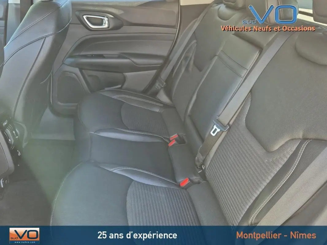 Vue intérieure arrière du Jeep Compass 2023 avec sièges noirs en tissu et cuir, ceintures de sécurité et porte côté gauche visible.