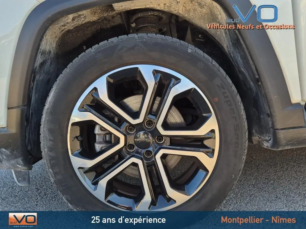 Gros plan sur la roue avant gauche du Jeep Compass blanc 2023 avec jante alliage 18 pouces bicolore.