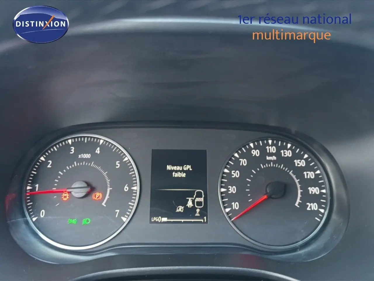 Gros plan sur le tableau de bord de la Dacia Sandero Stepway rouge, affichant un message d'alerte niveau GPL faible.