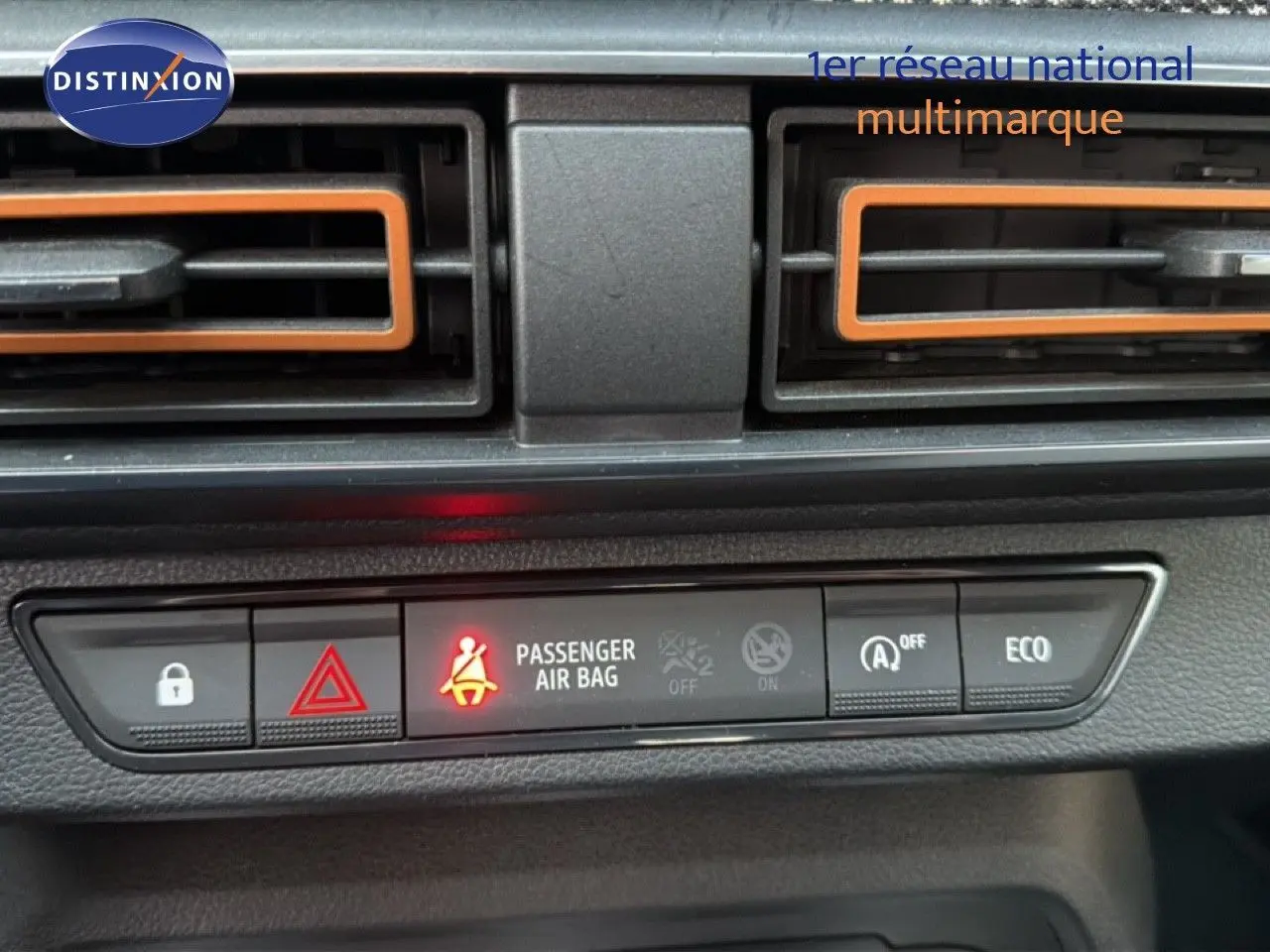 Vue rapprochée du tableau de bord de la Dacia Sandero Stepway rouge fusion, avec voyants et aérateurs orange visibles.