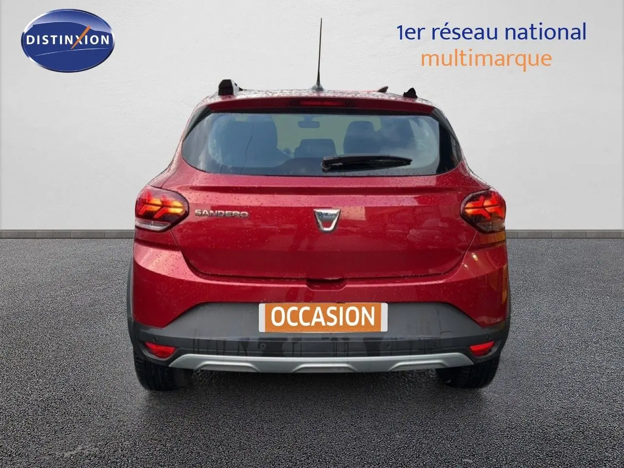 Vue arrière d'une Dacia Sandero Stepway rouge fusion 2021 avec feux allumés et plaque "OCCASION" visible.