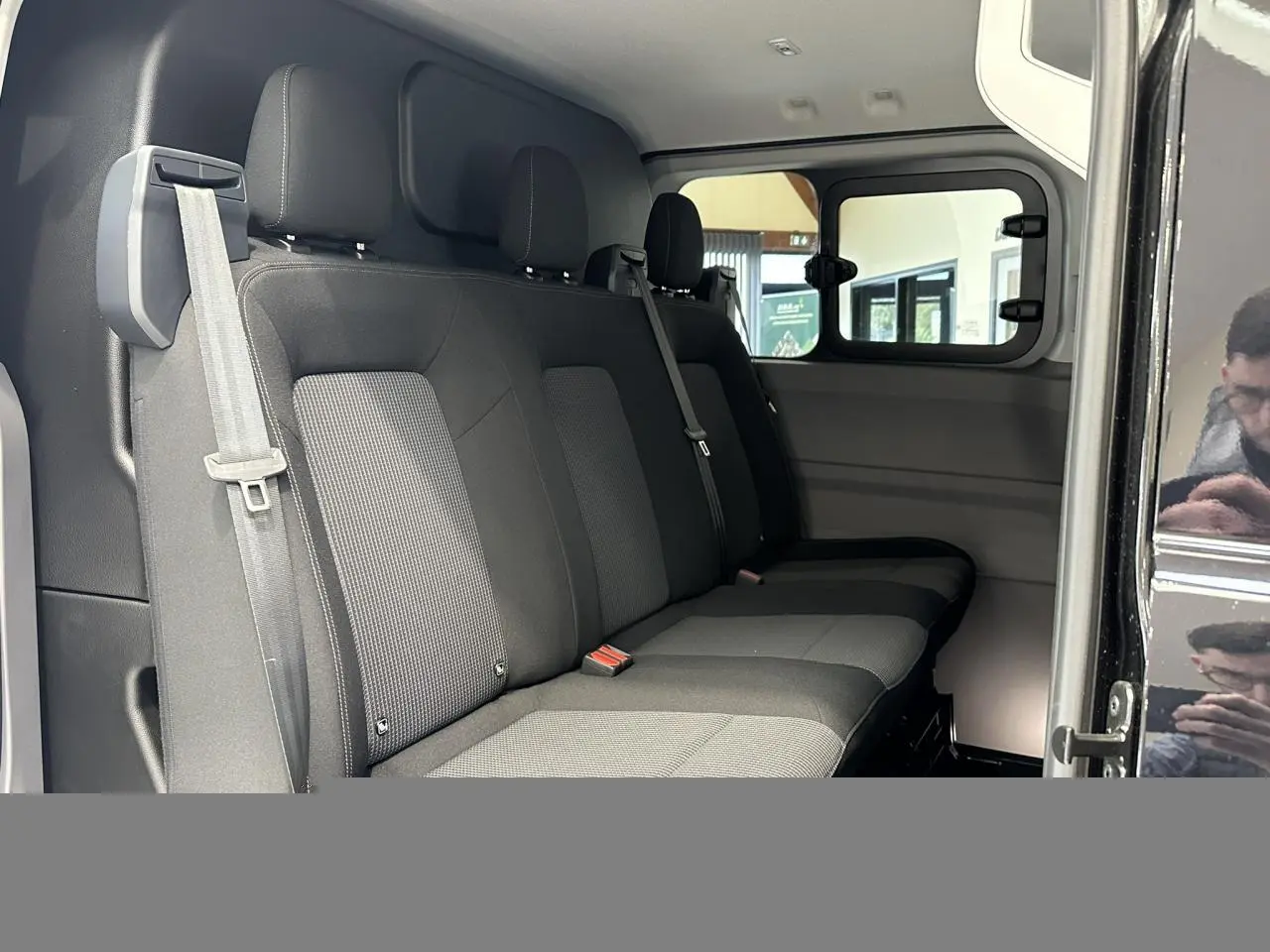 Vue intérieure côté droit du Volkswagen Transporter T7 ProCab 2026 noir Minuit, montrant la banquette arrière en tissu à rayures.
