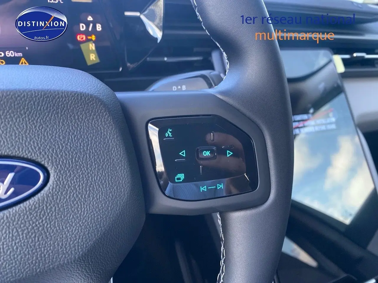 Gros plan sur les commandes tactiles du volant du Ford Explorer 2025, intérieur noir avec écran tactile visible en arrière-plan.