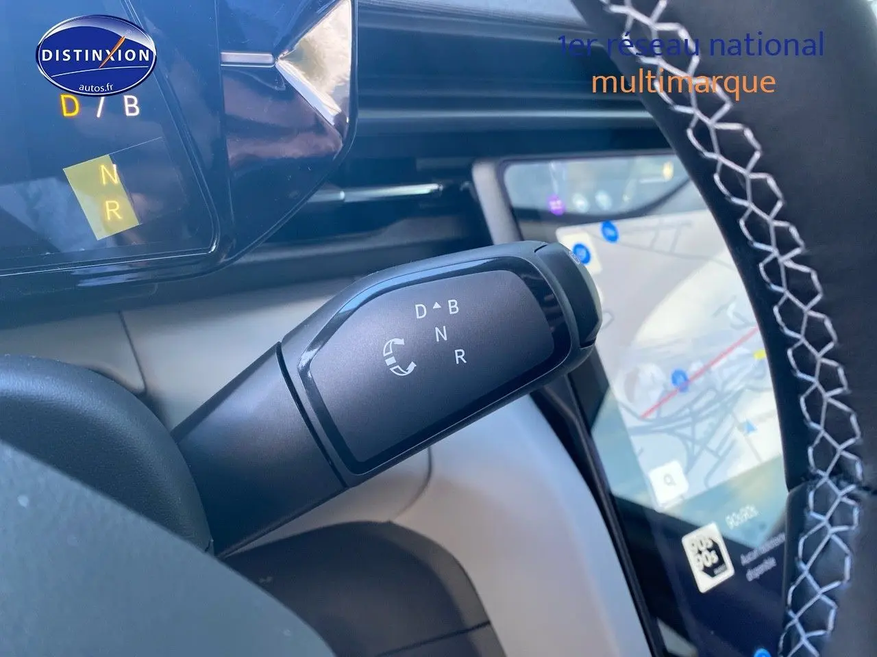 Gros plan sur la commande de boîte automatique du Ford Explorer 2025, volant avec surpiqûres blanches et écran tactile GPS visible.