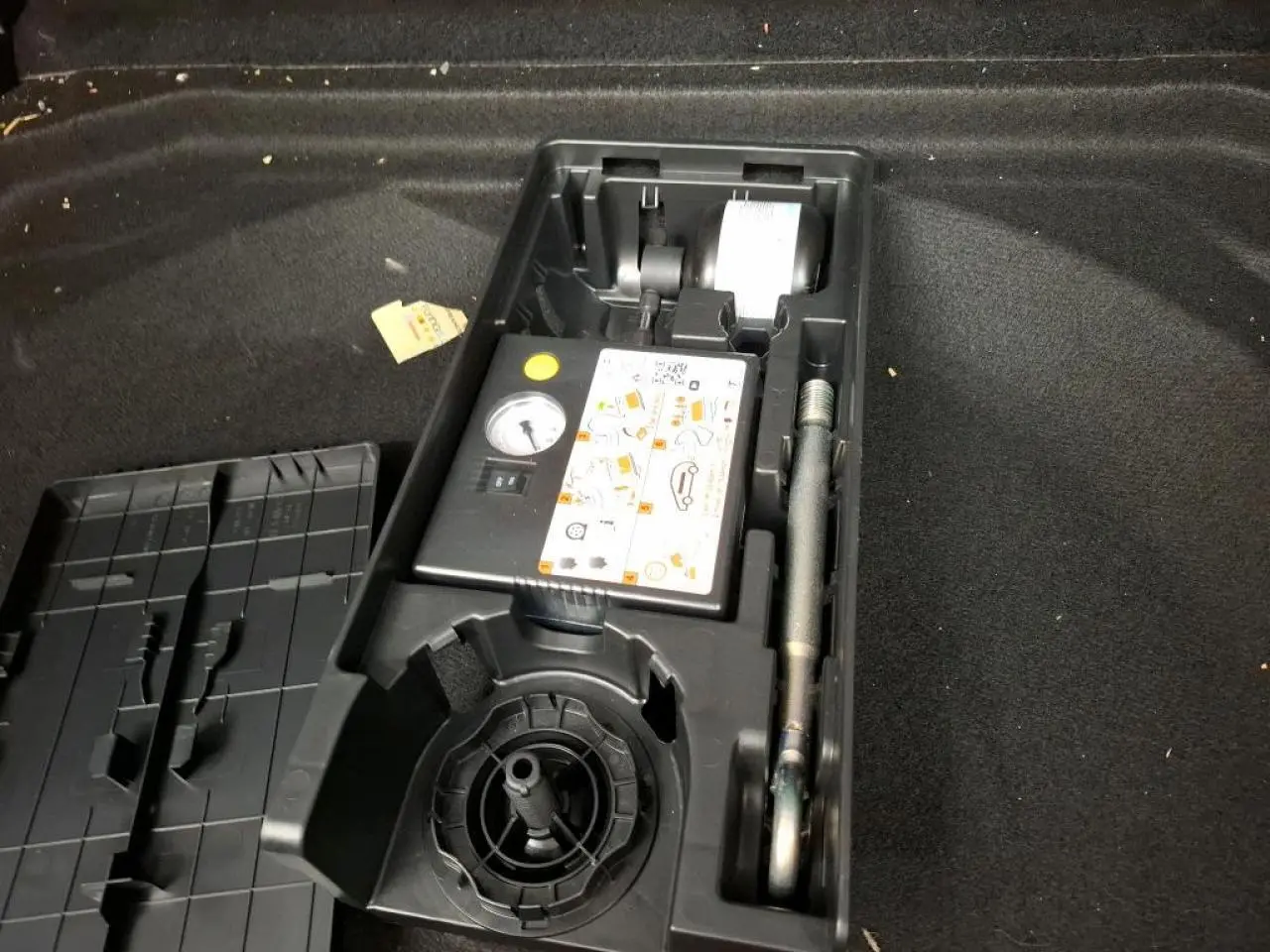 Coffre ouvert d’un Citroën C5 Aircross gris, montrant le kit de dépannage pneumatique rangé dans un compartiment noir.