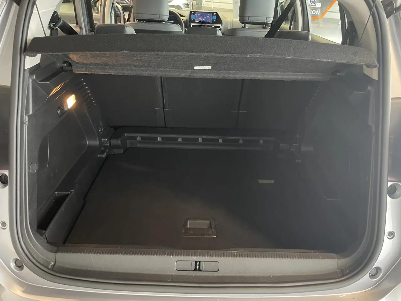Coffre ouvert vu de l'arrière d'un Citroën C5 Aircross gris Artense 2023, avec banquette arrière et tablette tactile visibles.