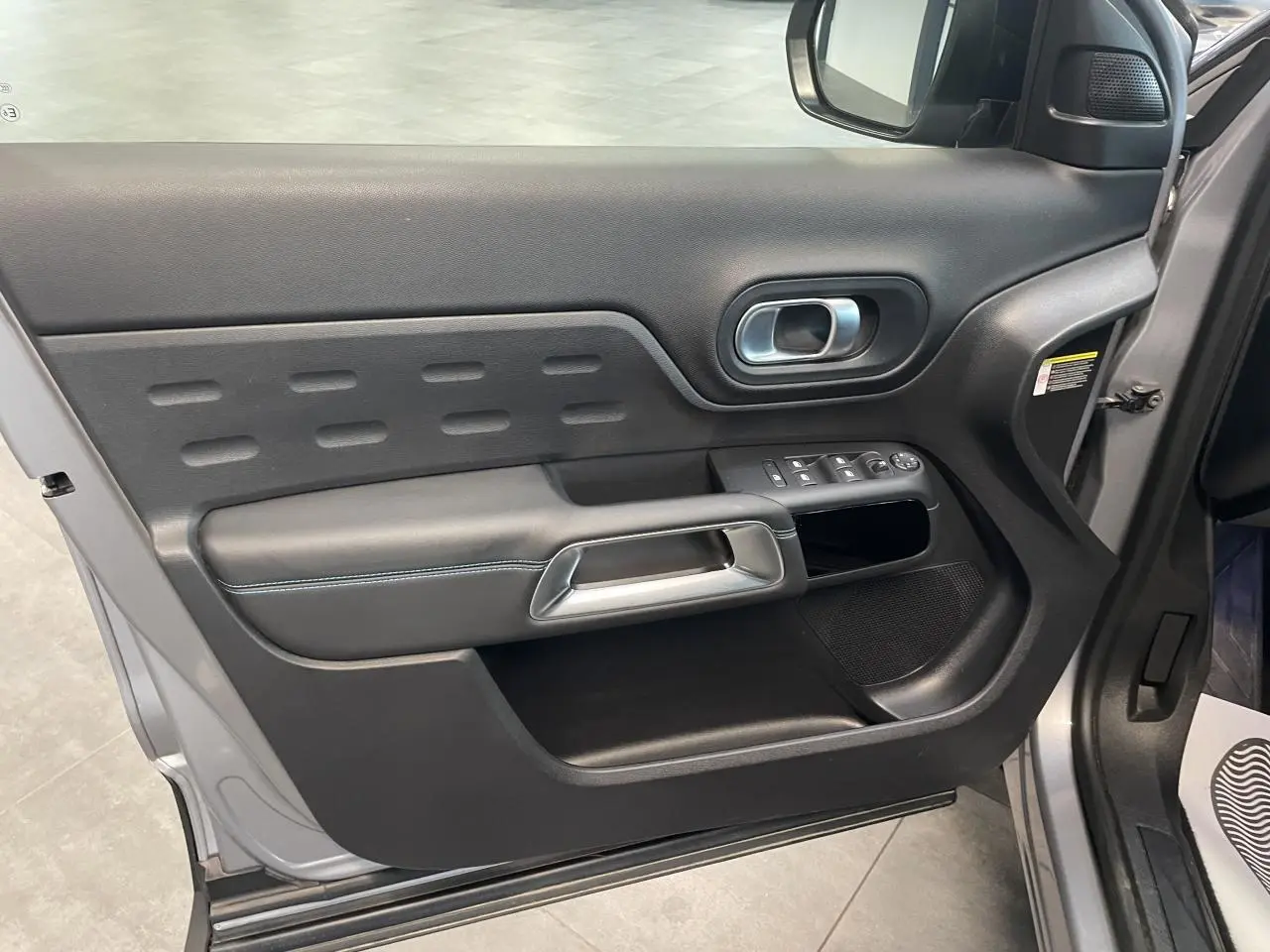 Vue rapprochée de la porte avant gauche gris Artense du Citroën C5 Aircross 2023 avec garniture noire et poignée métal.