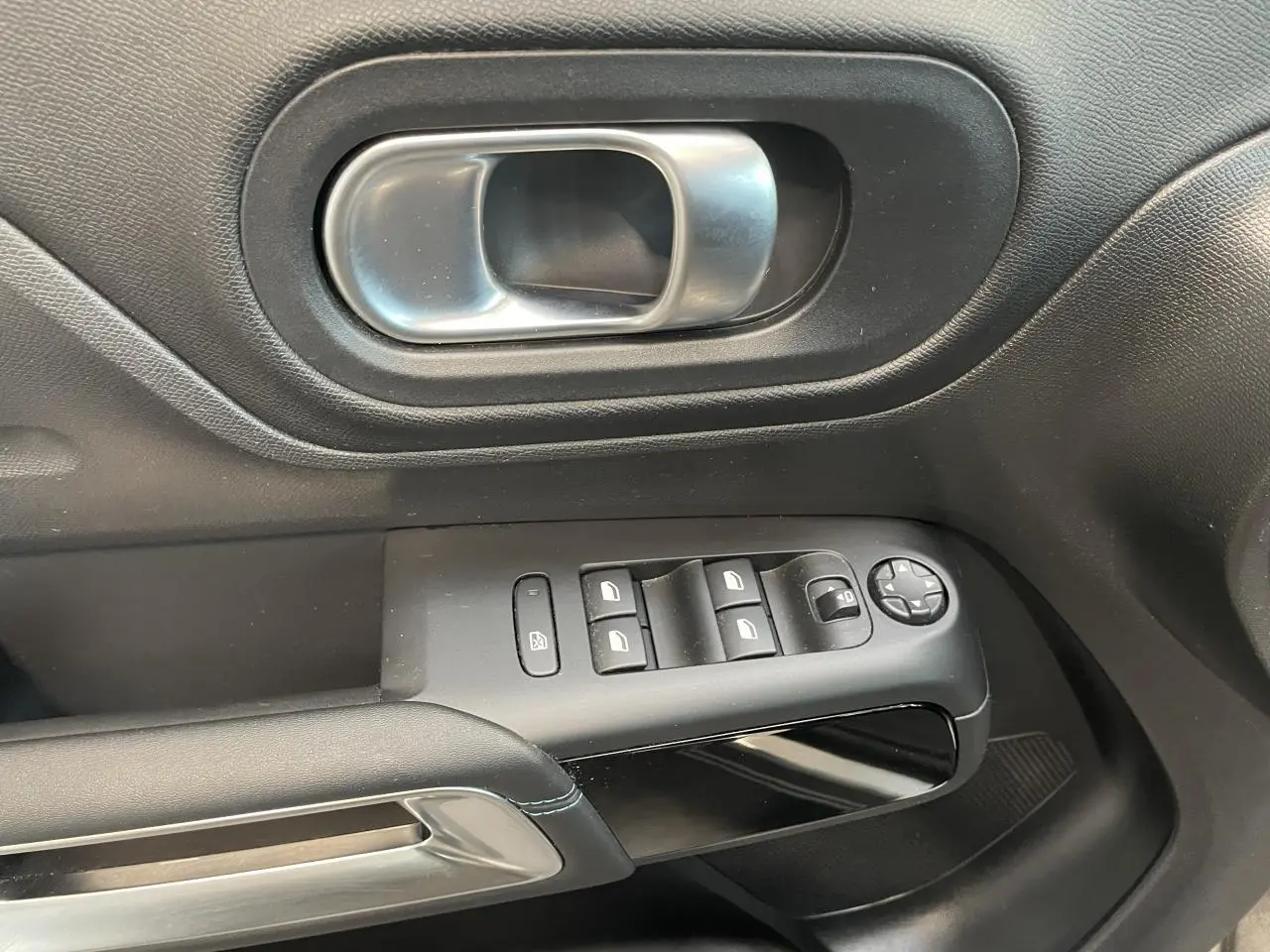 Gros plan sur la poignée intérieure et les commandes de vitres du côté gauche d’un Citroën C5 Aircross 2023 gris Artense.