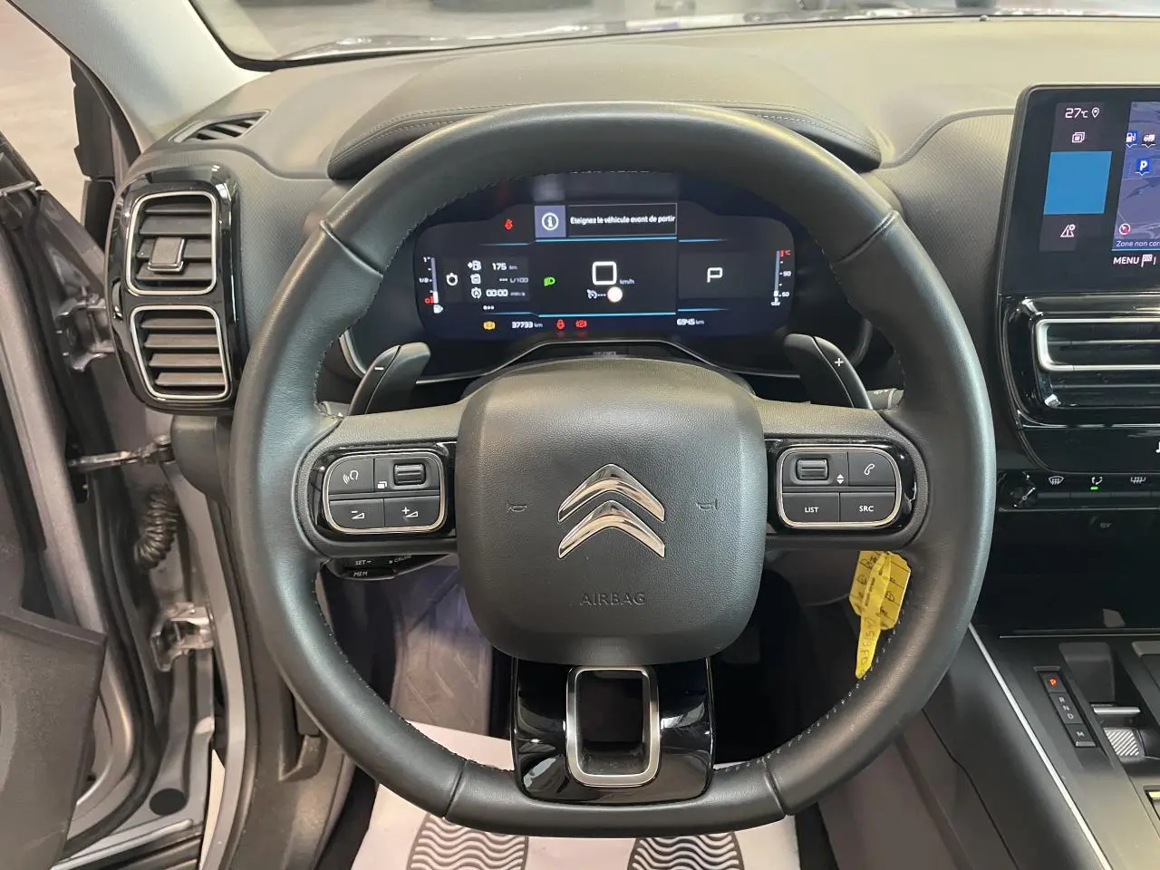 Vue intérieure centrée sur le volant cuir noir du Citroën C5 Aircross gris avec tableau de bord numérique et écran tactile.