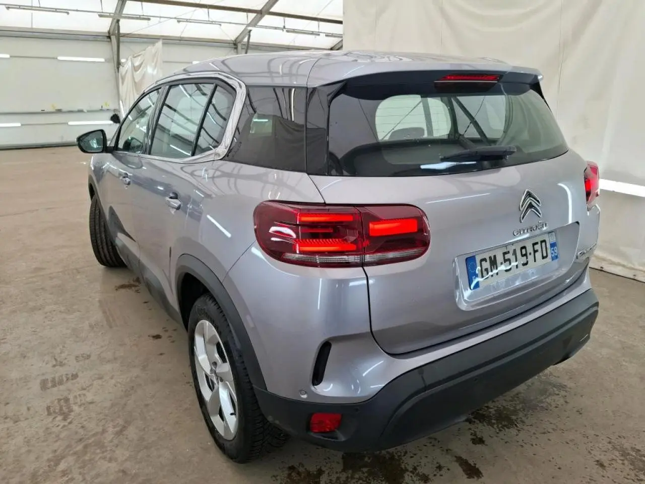 Vue 3/4 arrière droit du Citroën C5 Aircross gris Artense avec toit noir brillant et feux arrière LED 3D allumés.