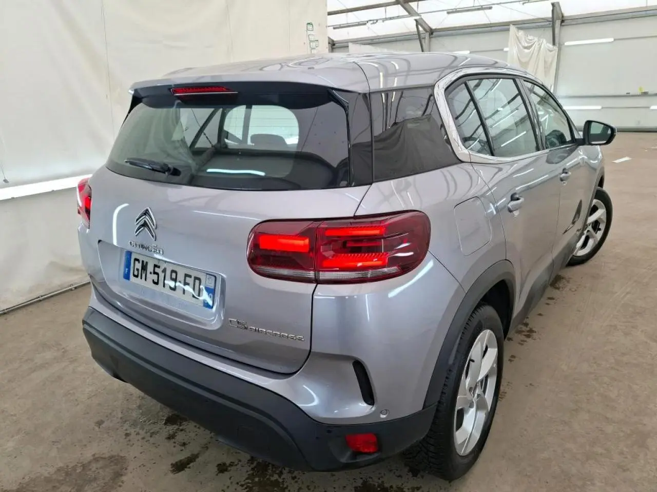Vue 3/4 arrière droite d'un Citroën C5 Aircross gris Artense avec toit noir brillant et feux arrière LED.