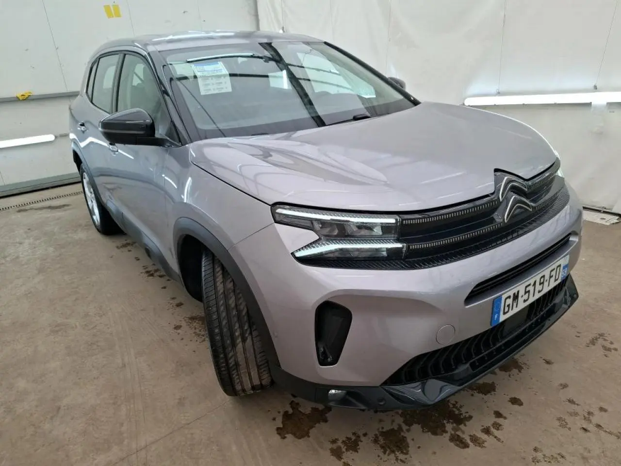 Vue 3/4 avant gauche du Citroën C5 Aircross gris Artense avec calandre noir brillant et feux LED distinctifs.