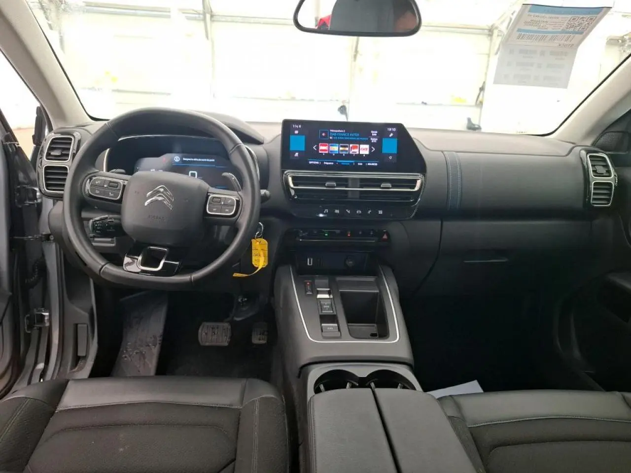 Vue intérieure avant du Citroën C5 Aircross gris Artense, tableau de bord moderne avec écran tactile central et volant multifonction.