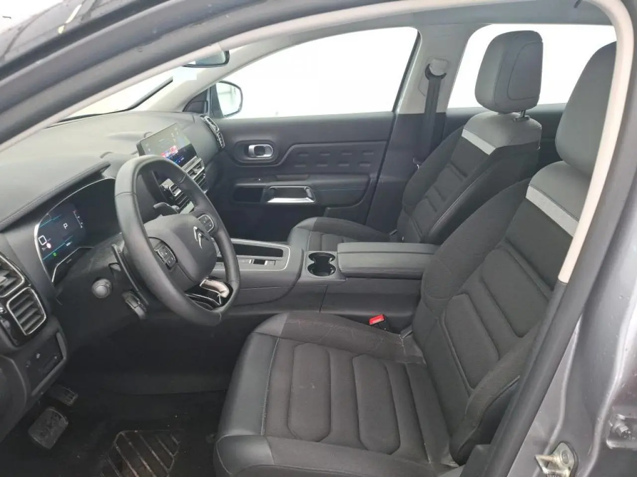 Vue intérieure côté conducteur du Citroën C5 Aircross gris Artense, sièges tissu noir avec surpiqûres grises et console centrale.