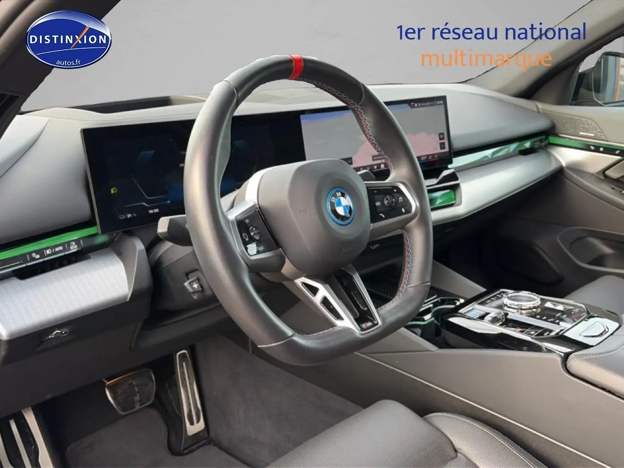 Intérieur BMW Série 5 i5 M60 2024 vu côté conducteur, volant sport cuir avec surpiqûres tricolores et tableau de bord digital.