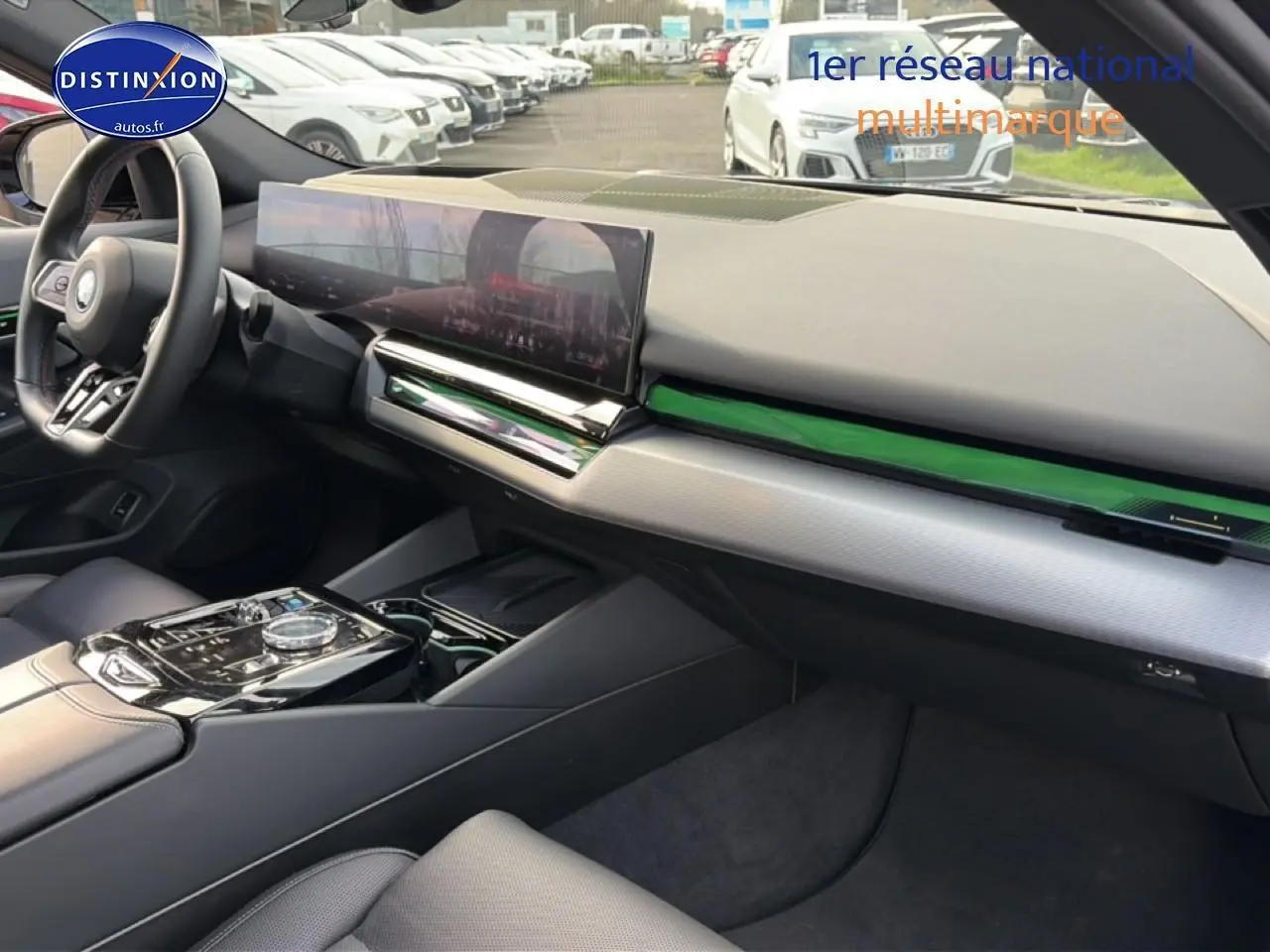 Vue intérieure côté passager de la BMW Série 5 i5 M60 noire 2024 avec tableau de bord moderne et écran tactile large.