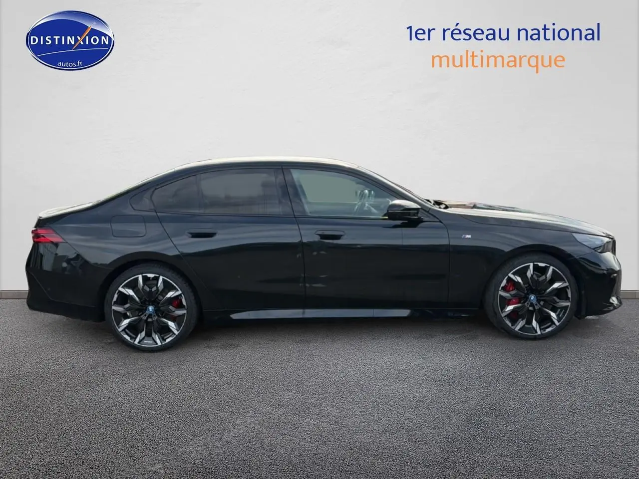 BMW Série 5 i5 M60 noir vue de profil côté gauche, avec jantes alu bicolores et étriers rouges visibles.