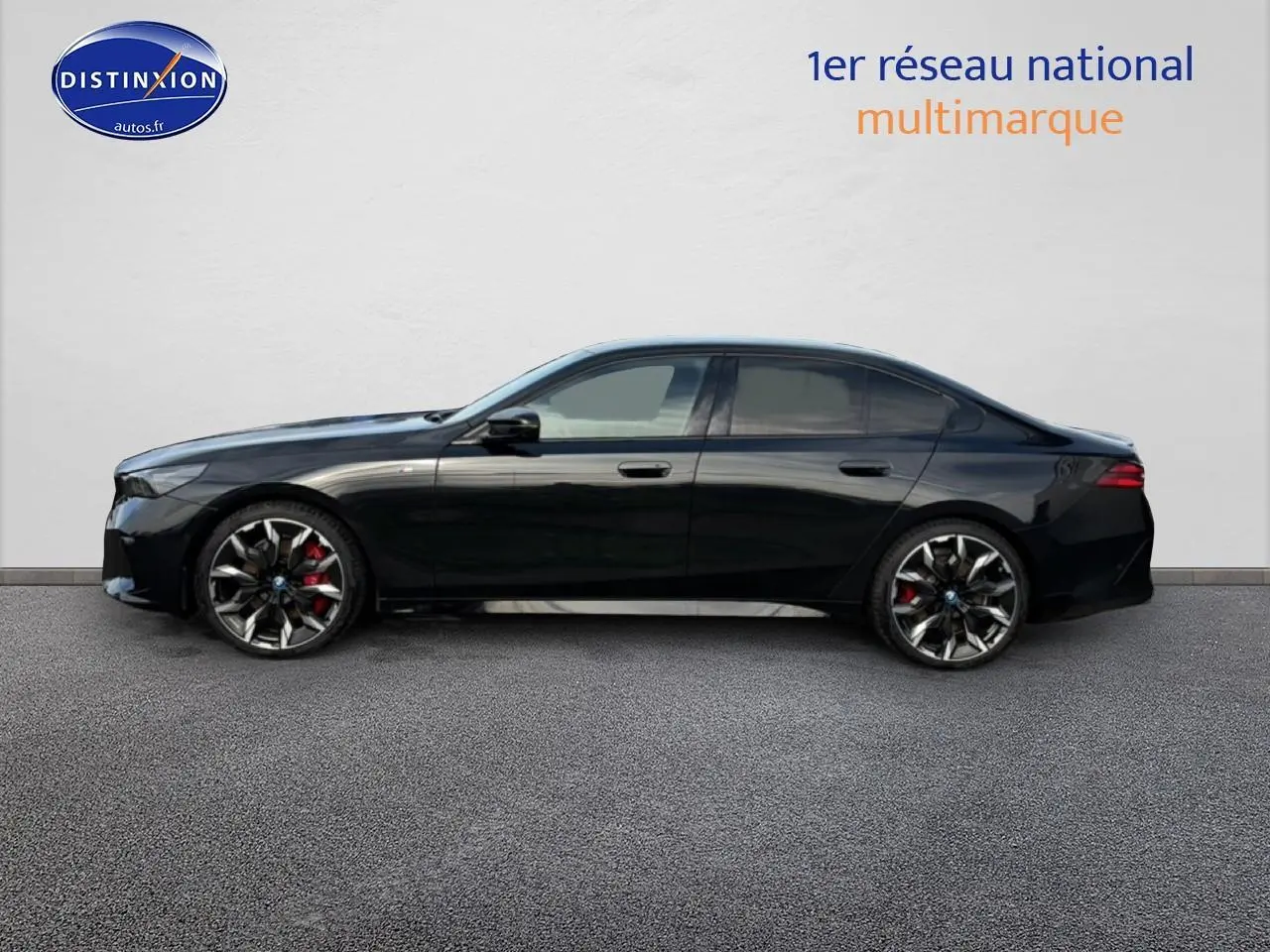 BMW Série 5 i5 M60 noire vue de profil côté gauche avec jantes alu bicolores et étriers rouges visibles.