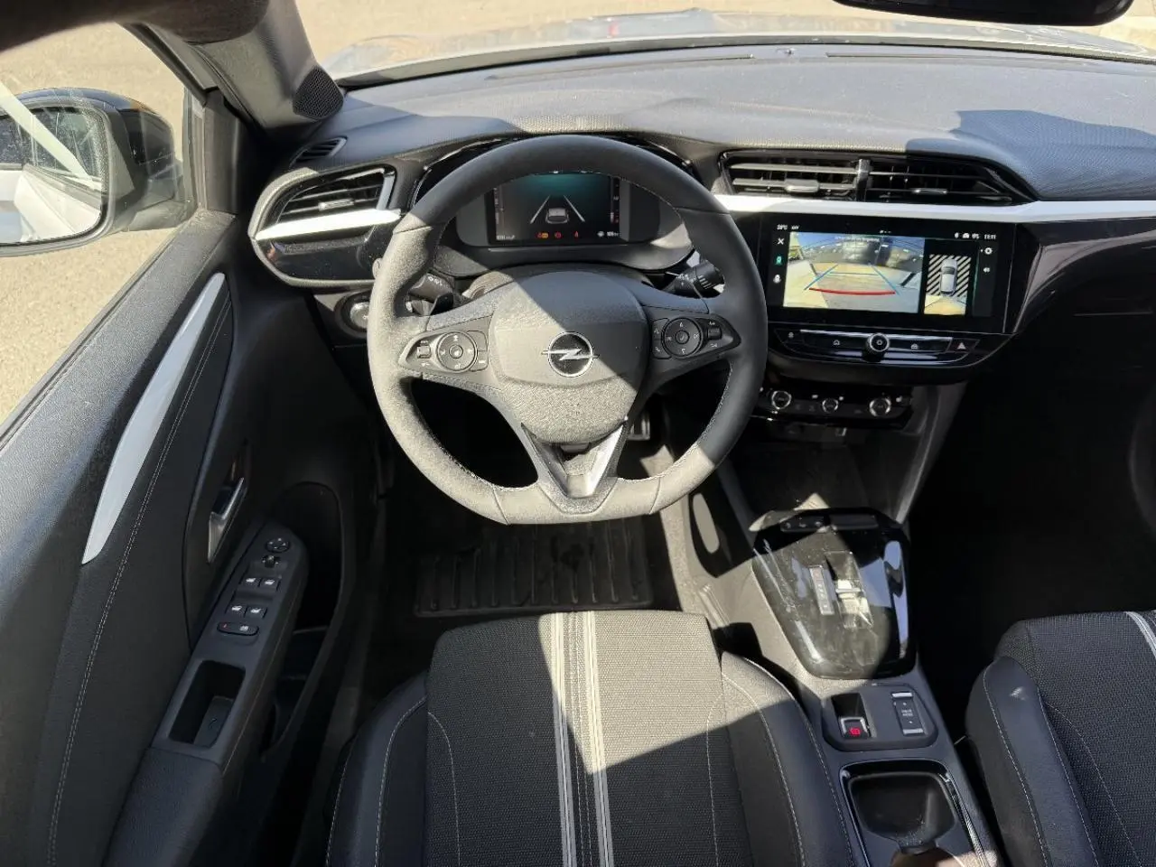 Intérieur Opel Corsa 1,2 Hybrid 2025 vu du dessus, tableau de bord noir avec écran tactile et volant multifonction.