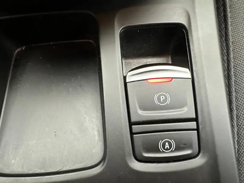 Gros plan sur les commandes de frein à main électrique et auto hold dans l'habitacle du Renault Arkana 2025.