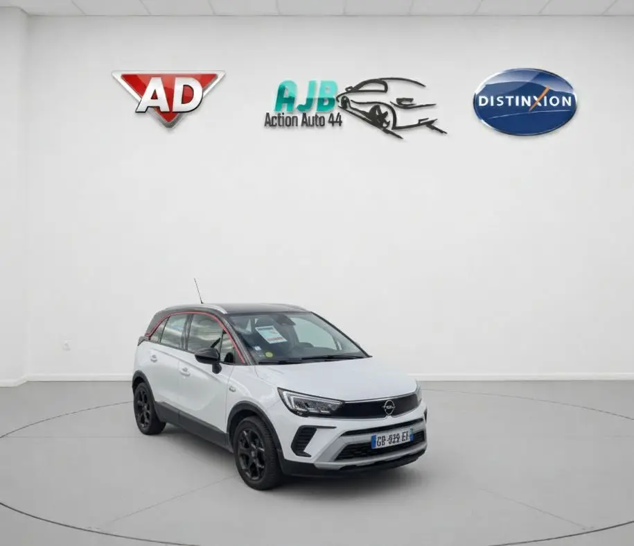 Opel Crossland X blanc 3/4 avant droit avec toit noir et jantes noires dans un studio blanc.