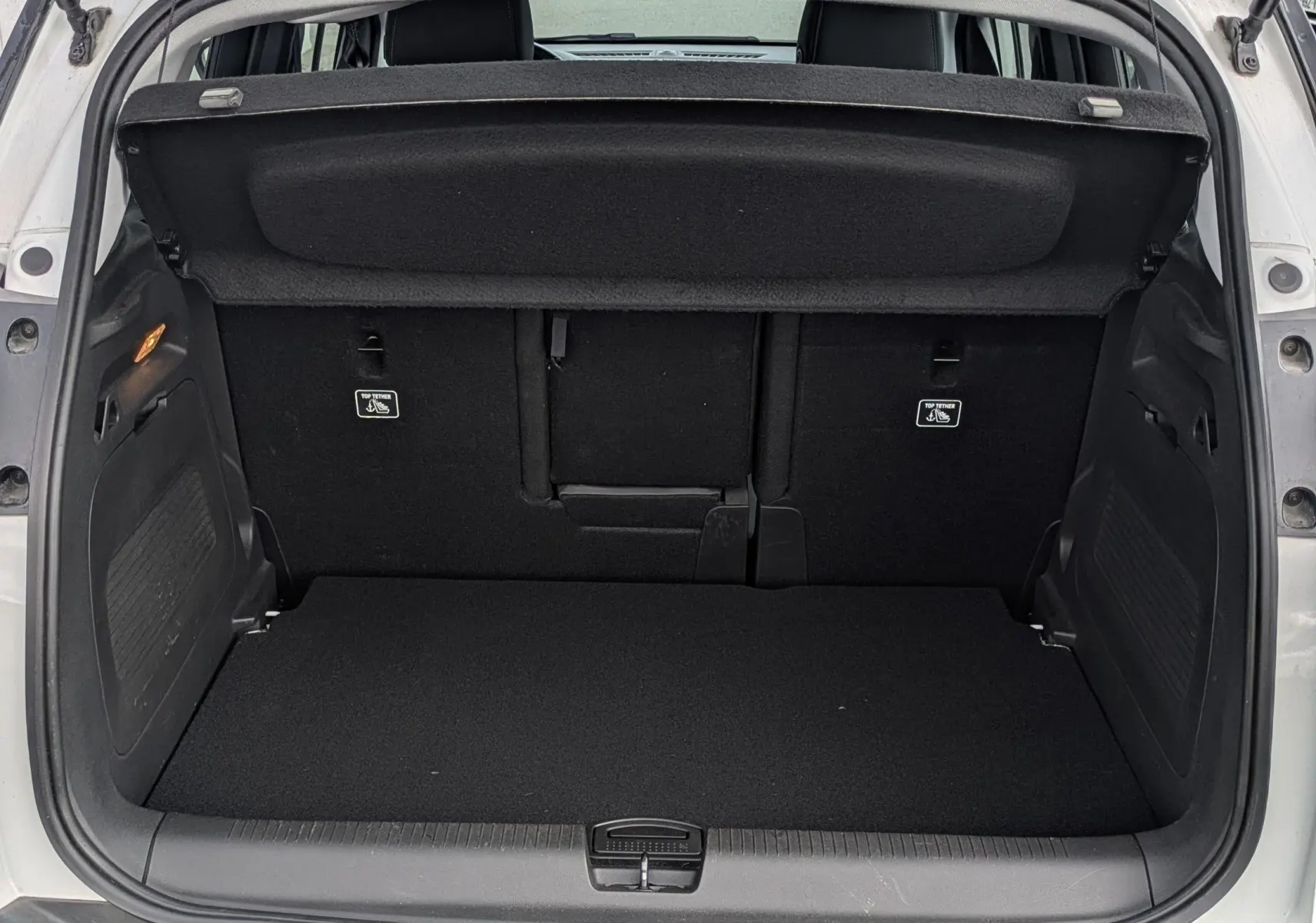 Coffre ouvert d'un Opel Crossland X blanc, vue arrière montrant l'espace de chargement et la tablette cache-bagages noire.
