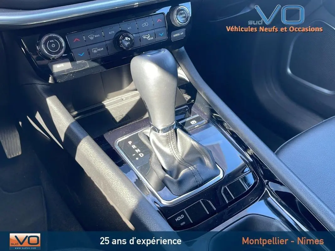 Gros plan sur la console centrale noire du Jeep Compass 2023, mettant en valeur le levier de vitesse automatique et les commandes climatisation.