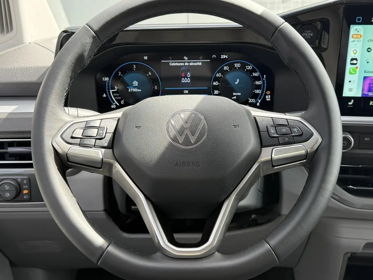 Vue rapprochée du volant multifonction noir du Volkswagen Transporter T7 avec tableau de bord numérique et écran tactile latéral.