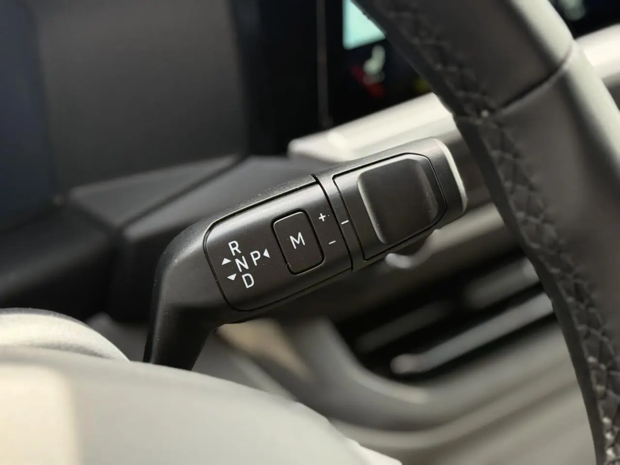 Gros plan sur le levier de vitesses automatique noir à commandes blanches, côté droit du volant du Volkswagen Transporter gris argent.