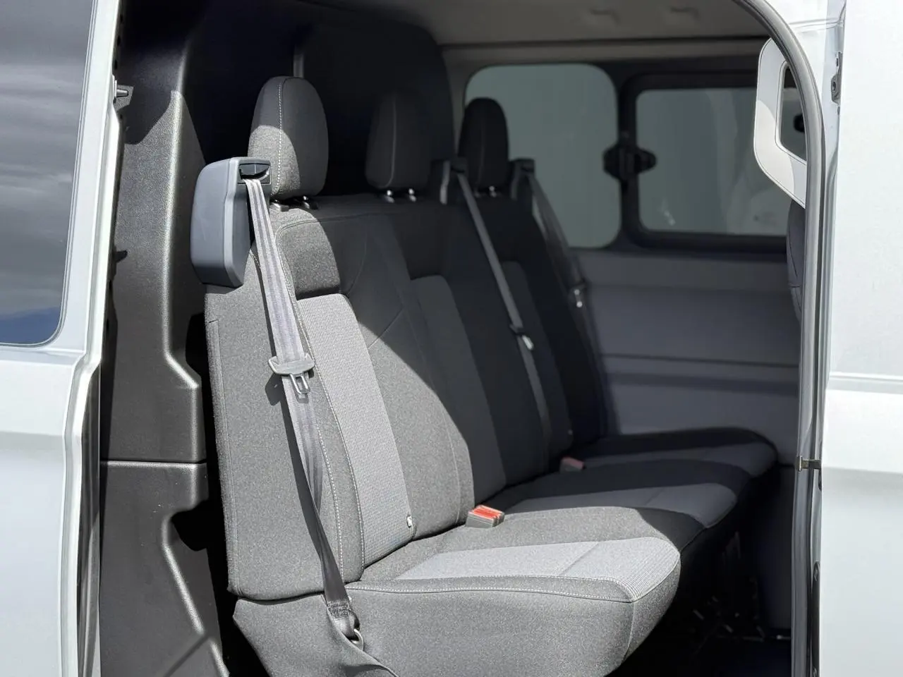 Vue intérieure côté gauche du Volkswagen Transporter T7 ProCab gris argent, montrant la banquette arrière en tissu gris.