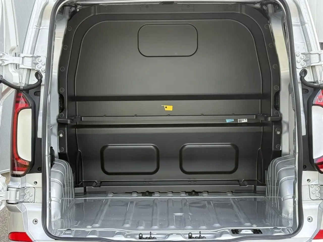 Vue arrière du Volkswagen Transporter T7 ProCab gris argent, montrant l'espace de chargement vide et la cloison noire.