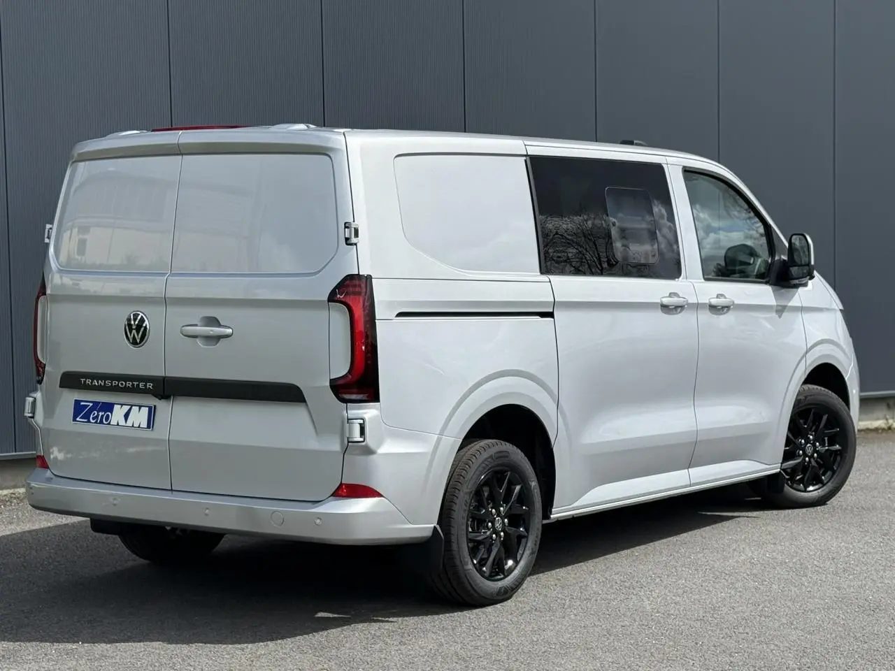 Vue 3/4 arrière droite d’un Volkswagen Transporter T7 ProCab gris argent avec jantes noires et feux arrière LED.