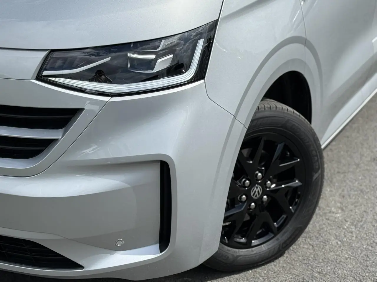 Gros plan sur l'avant droit gris argent du Volkswagen Transporter T7 avec jante alliage noir brillant et phare LED Matrix.