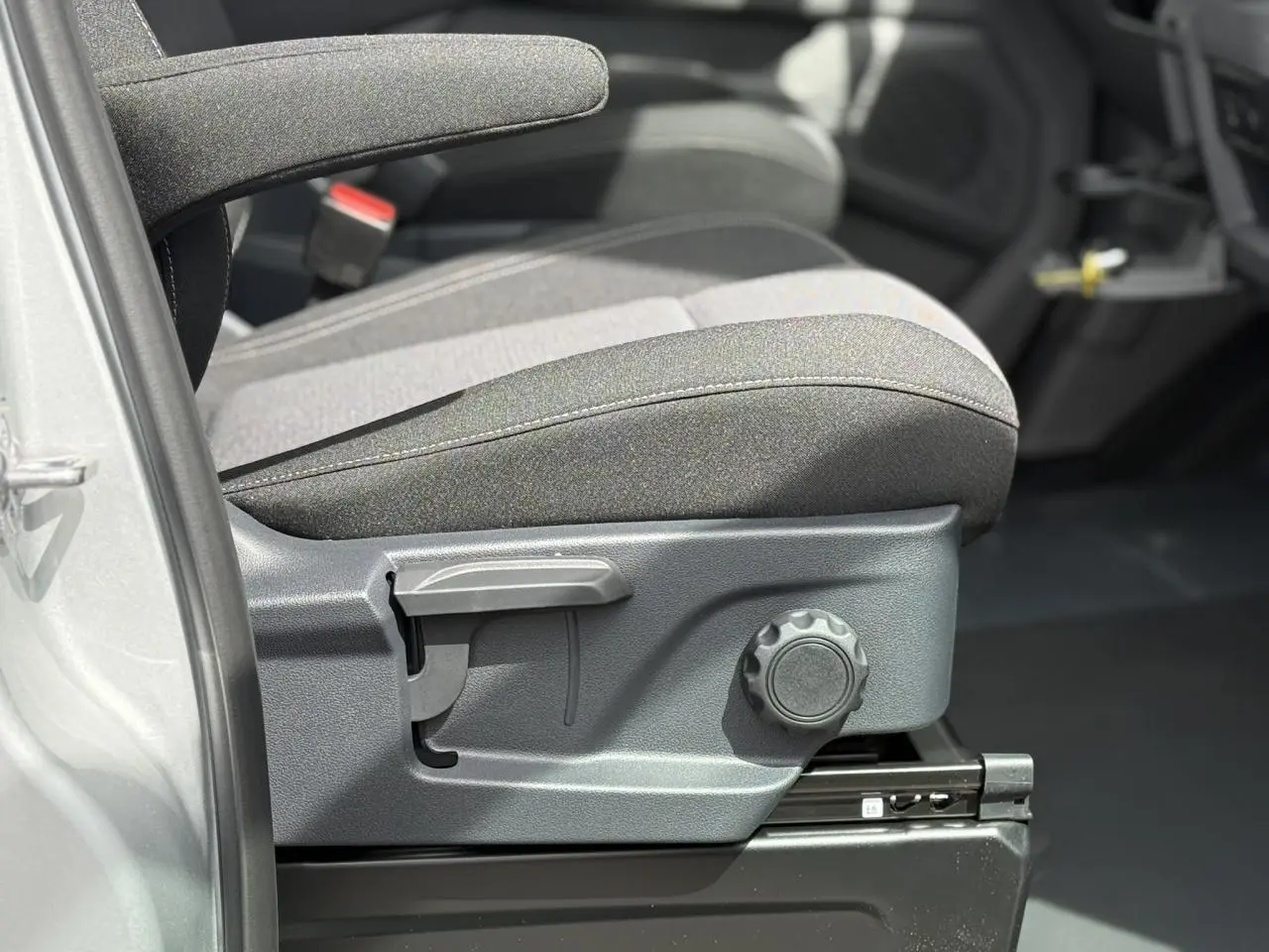 Détail du siège avant côté conducteur du Volkswagen Transporter T7 gris argent avec réglages manuels visibles.