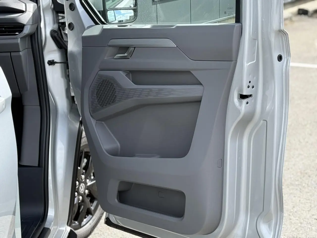 Vue rapprochée de la porte avant gauche gris argent du Volkswagen Transporter T7 avec jante alliage noir brillant visible.