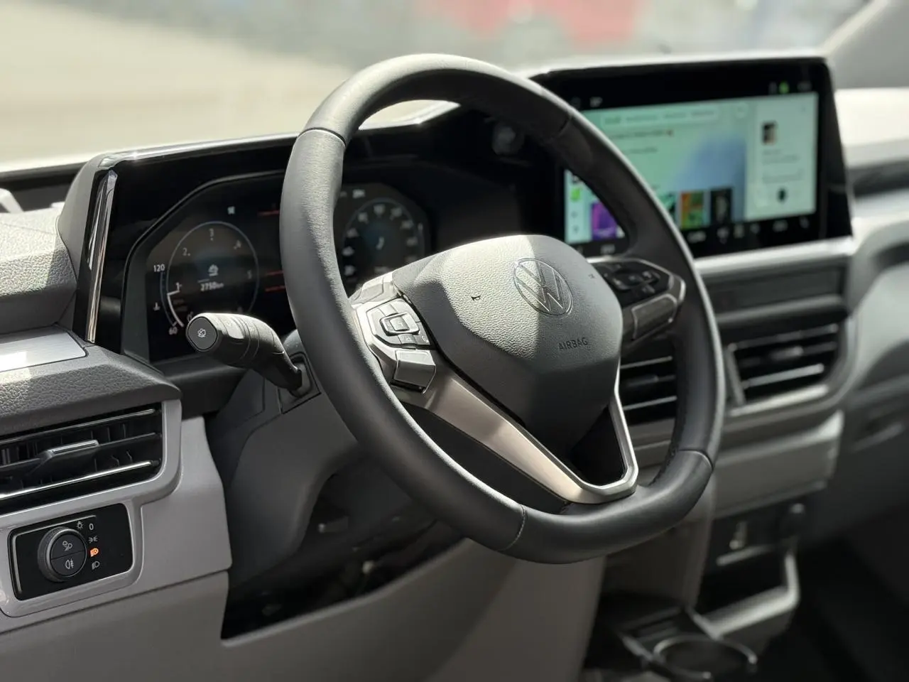 Vue rapprochée du volant multifonction noir et du tableau de bord digital du Volkswagen Transporter T7 2026.