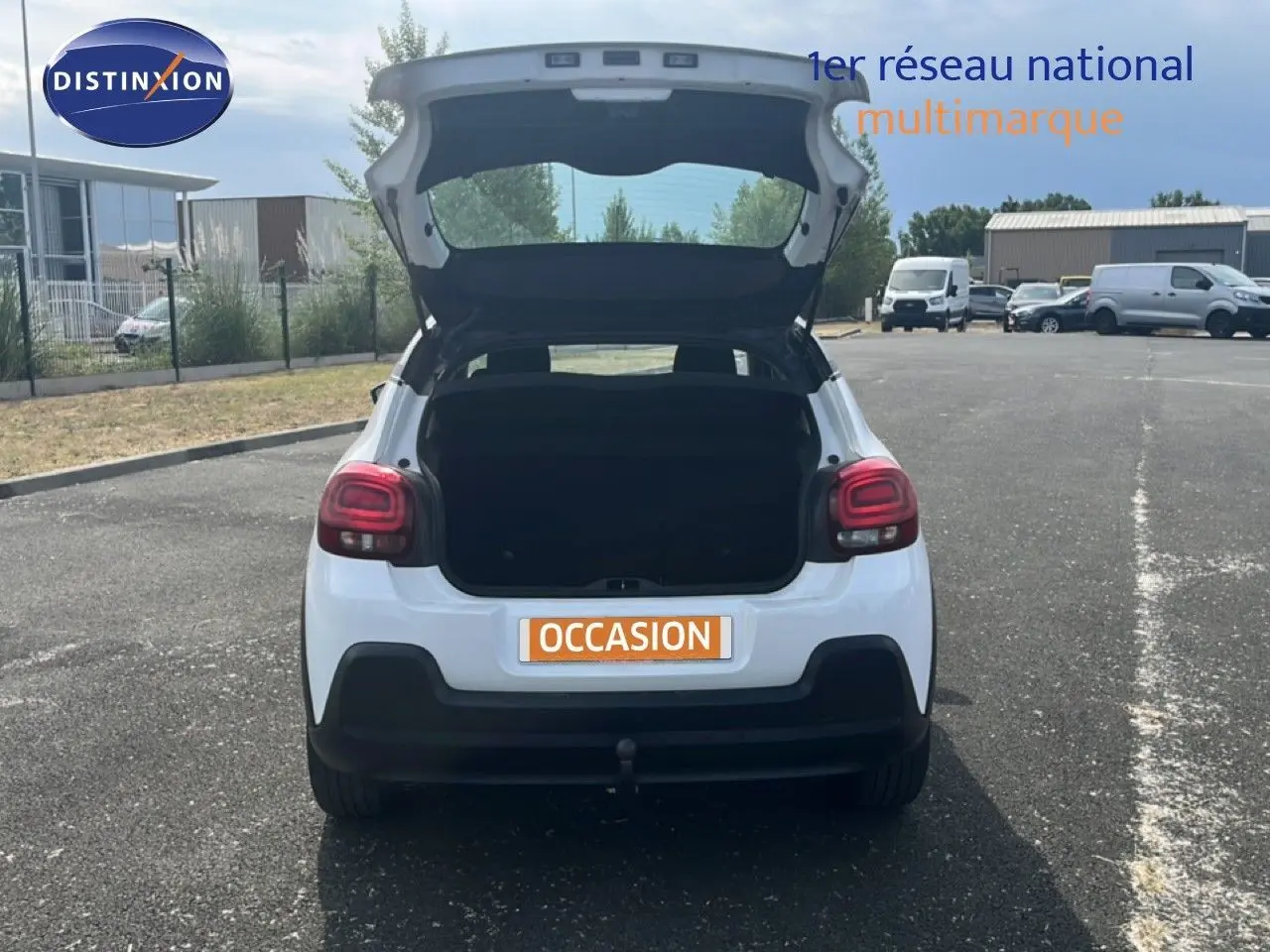 Vue arrière d'une Citroën C3 blanche de 2018 avec coffre ouvert sur un parking extérieur.