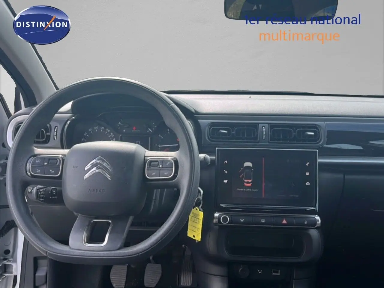 Vue intérieure frontale du tableau de bord noir et volant Citroën C3 blanc 2018 avec écran tactile central allumé.