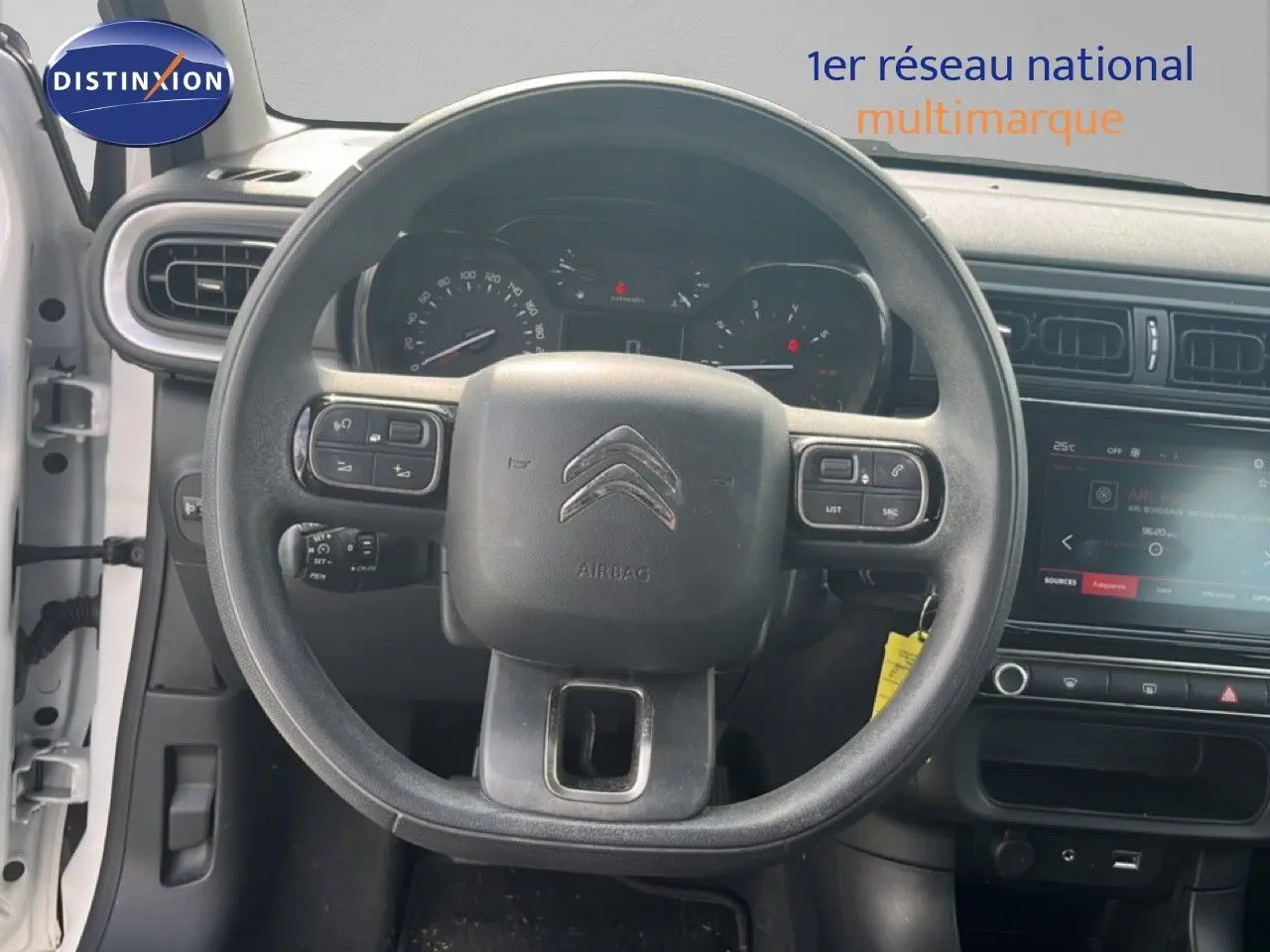 Vue intérieure centrée sur le volant noir d'une Citroën C3 blanche de 2018 avec tableau de bord et écran tactile.