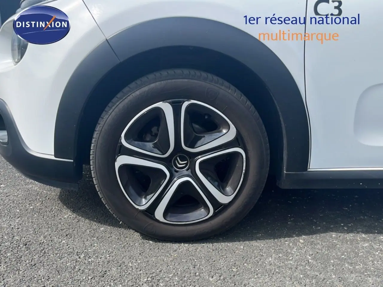 Gros plan sur la roue avant gauche d'une Citroën C3 blanche de 2018 avec jante alliage noire et argentée.