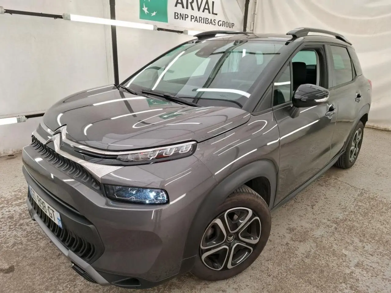 Citroën C3 Aircross gris foncé en 3/4 avant droit avec barres de toit noires et jantes 16 pouces.
