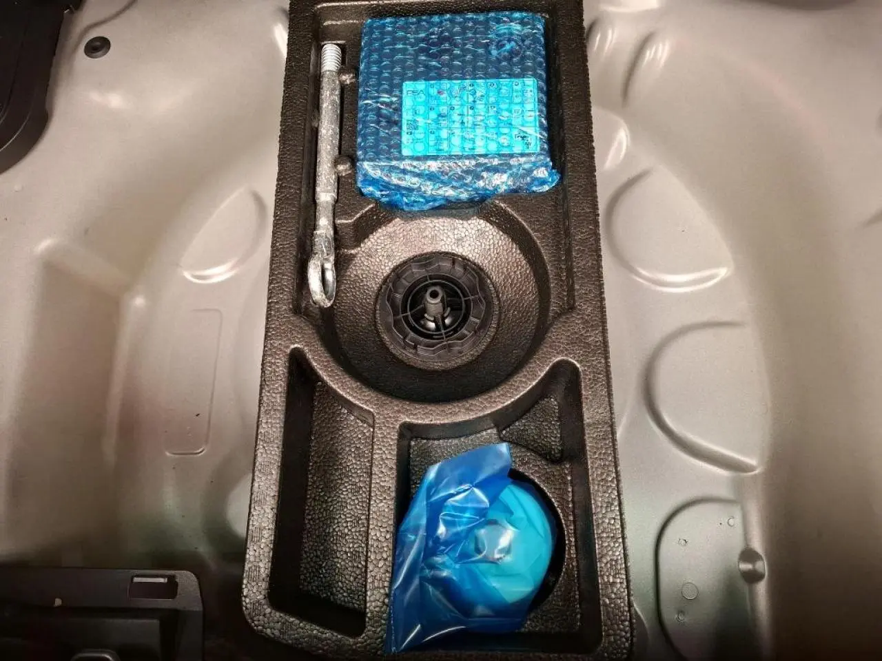 Vue plongeante sur le coffre d’un Citroën C3 Aircross 2023 gris foncé, montrant le rangement pour roue de secours.