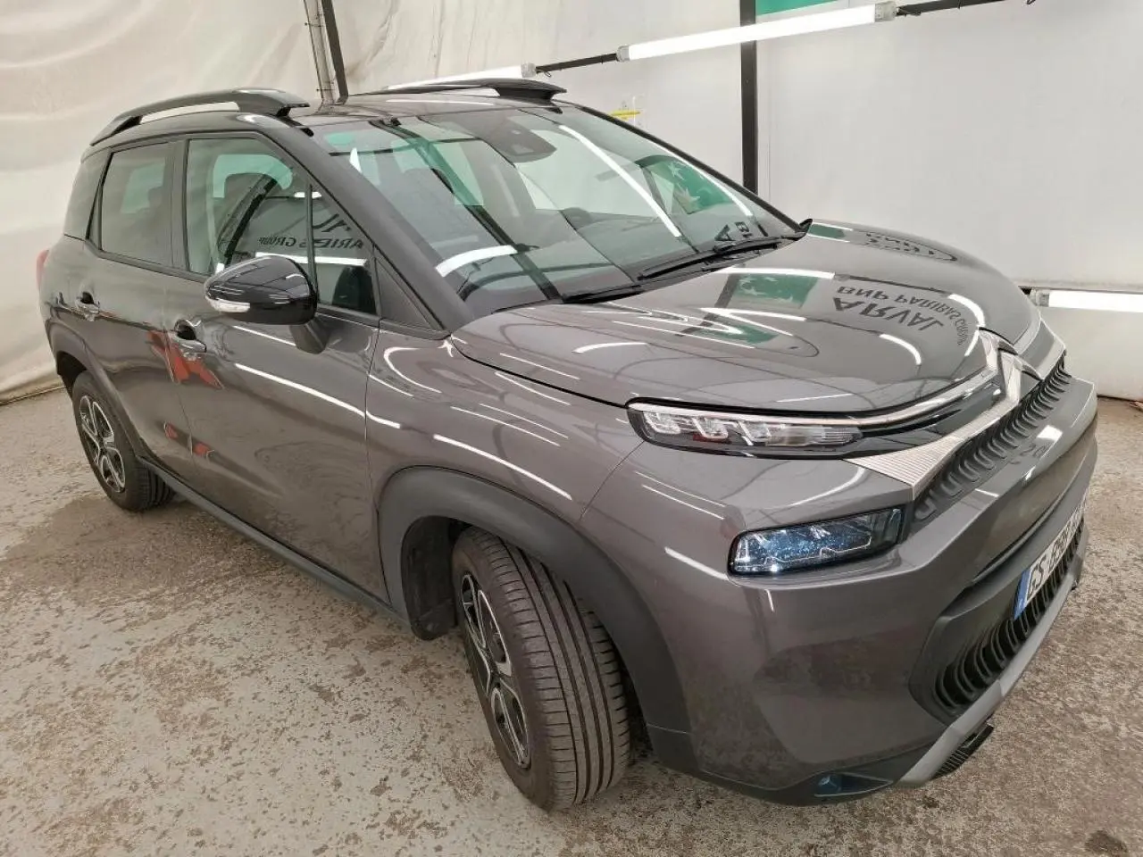 Citroën C3 Aircross gris foncé vue 3/4 avant droit, avec barres de toit noires et jantes 16 pouces design.