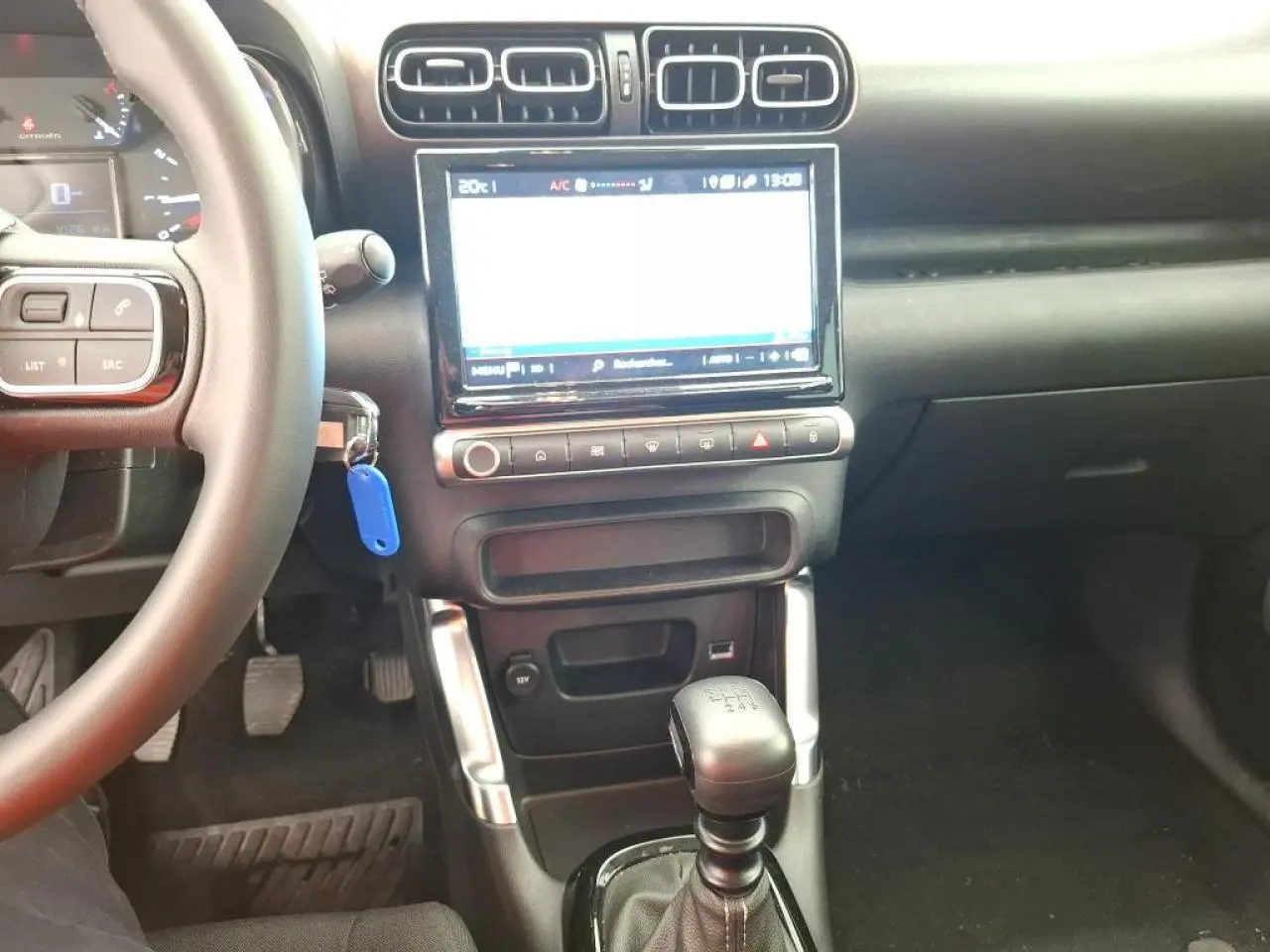 Vue intérieure centrée sur la console centrale et levier de vitesses manuelle du Citroën C3 Aircross 2023 gris foncé.