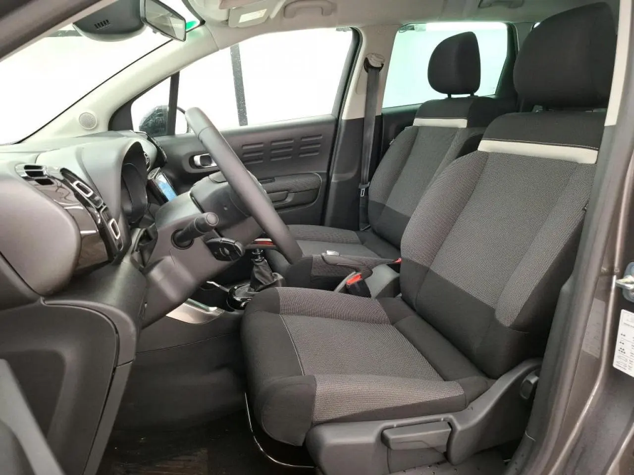 Intérieur avant du Citroën C3 Aircross gris foncé, vue côté conducteur avec sièges tissu Mica Grey et volant cuir.